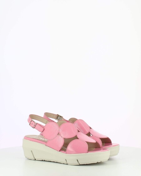 Pink Patent sling back wedge sandal with cutouts on a white base.