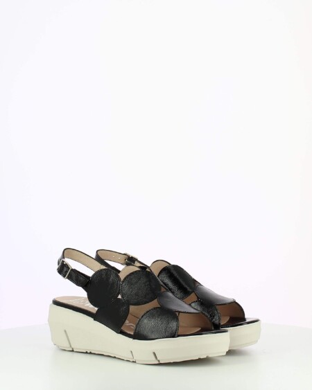 Black Patent sling back wedge sandal with cutouts on a white base.