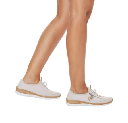 Stylish white sneakers on a woman's legs, featuring Rieker Nabukino canvas material for a trendy and comfortable look.