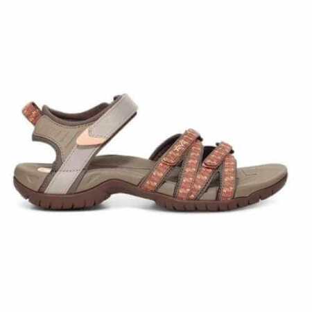A stylish and rugged outdoor Tirra sandal by Teva with adjustable straps in earthy tones. The sandal features a durable, textured sole for traction, and a mix of beige and brown colors with red accents on the straps. Perfect for hiking or casual wear.