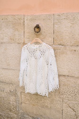 Cream CRLhilla Lace Blouse in white hanging on a brick wall